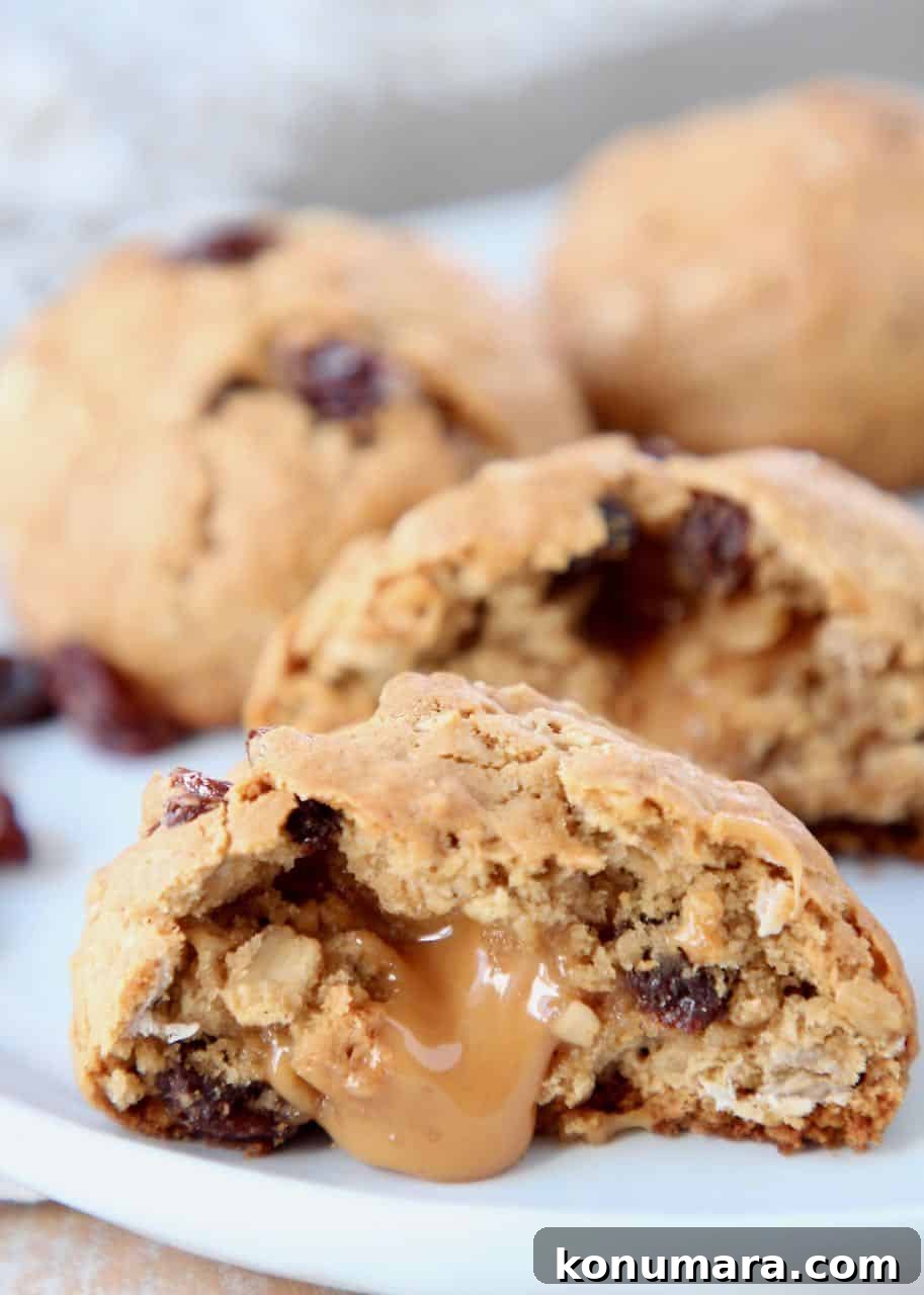 Oatmeal raisin cookie cut in half with caramel oozing out of the middle
