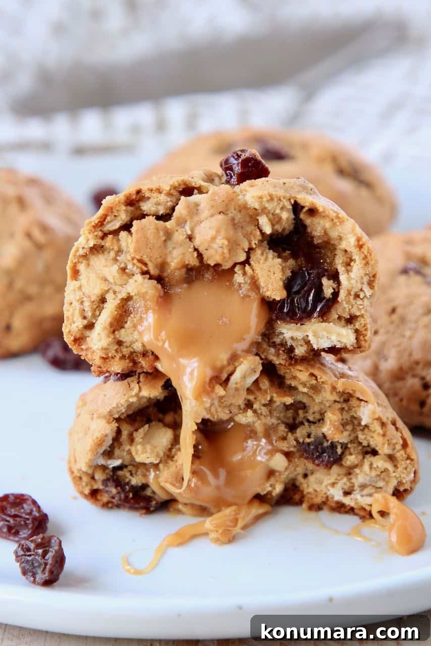 Oatmeal raisin cookies with caramel center cut in half stacked on top of each other