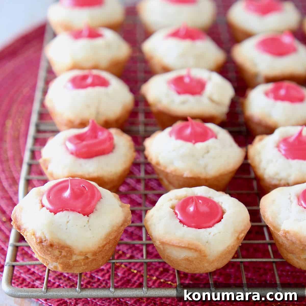 Sugar cookie cups with red frosting filling sitting on wire rack