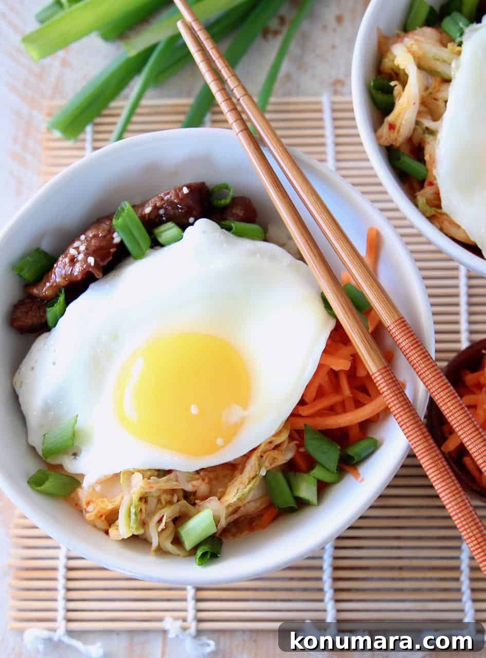 Korean BBQ Cauliflower Rice Bowl with Gochujang Glaze 3 Korean BBQ Cauliflower Rice Bowl topped with a fried egg with chopsticks and green onions