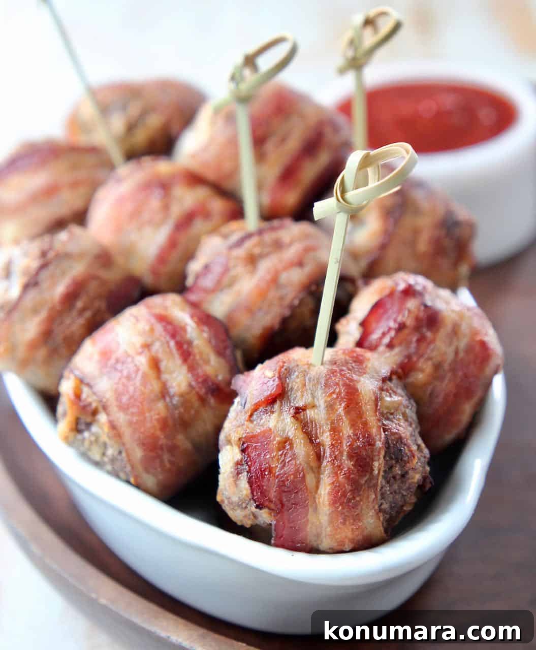 Bacon wrapped meatballs in bowl with wood skewers