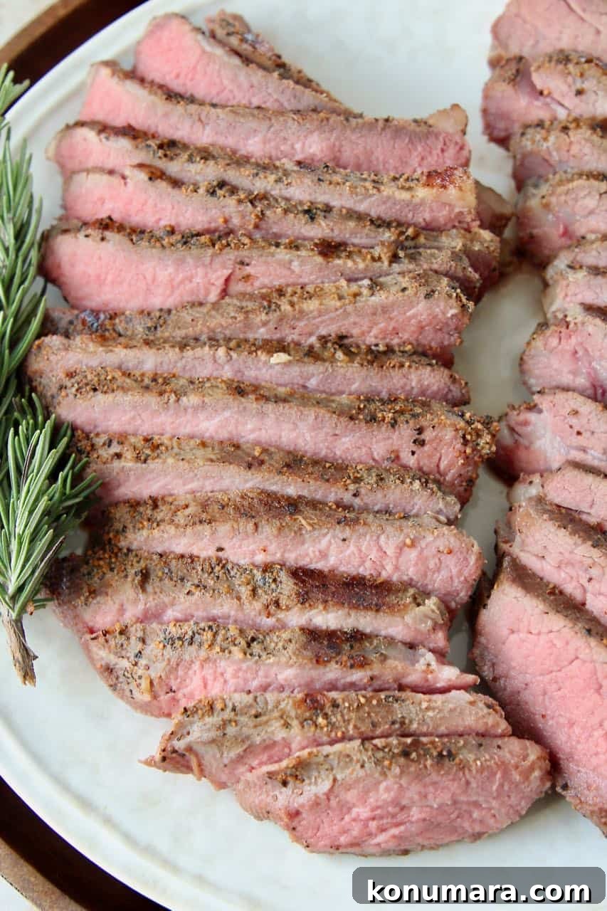 Sliced sous vide tri tip steak on plate with rosemary sprigs