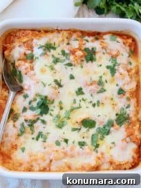 Cheesy buffalo chicken cauliflower casserole with spoon, topped with cilantro