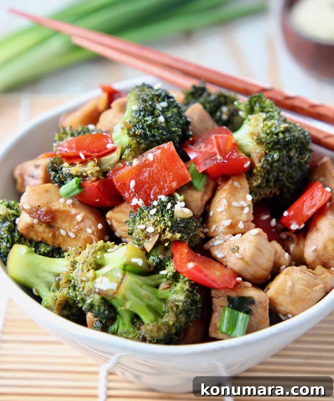 Stir fry teriyaki chicken and broccoli in white bowl with chopsticks on the side