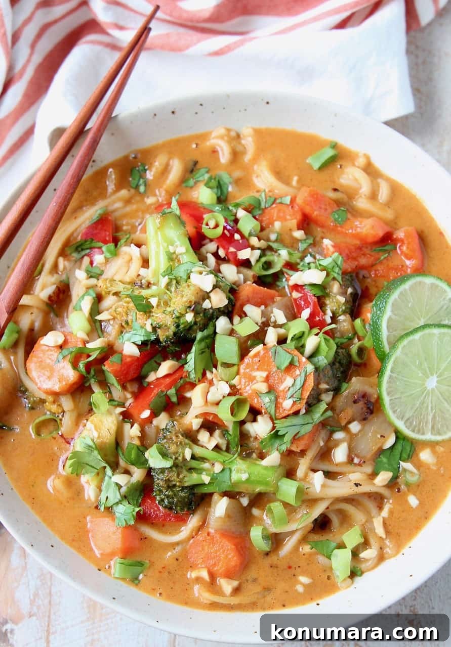 Overhead image of vegetable massaman curry in bowls with noodles and lime wedges