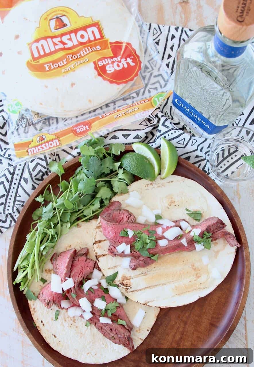 Grilled Citrus-Marinated Carne Asada 5 Carne asada tacos on wood tray with fresh cilantro