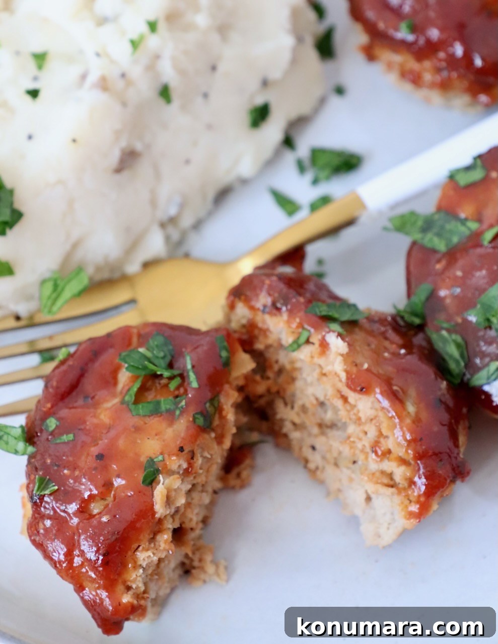 Maple-Glazed Mini Meatloaves Recipe 10 mini meatloaf sliced in half on plate with fork and mashed potatoes