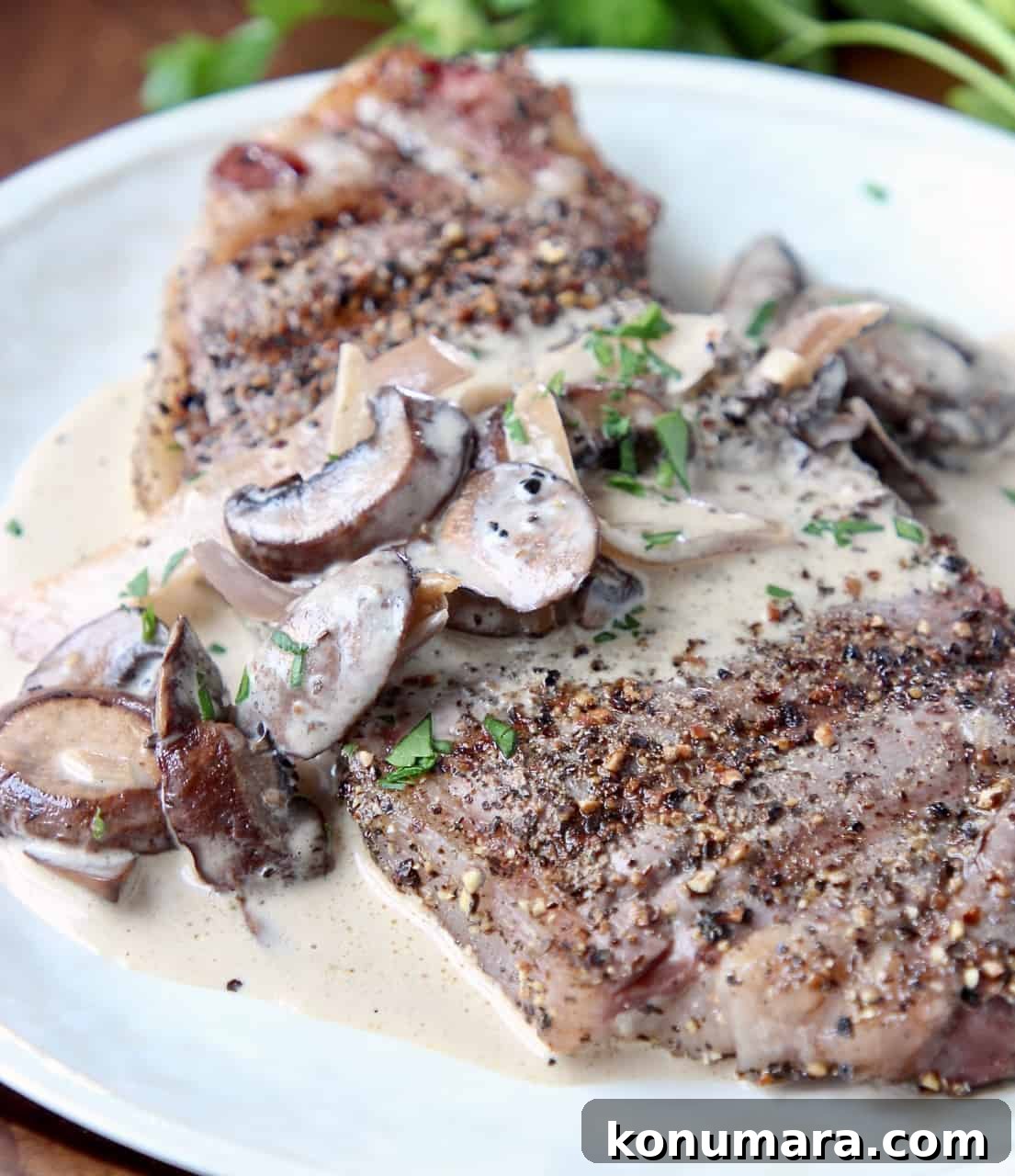 Grilled Peppercorn Crusted New York Strip with Mushroom Sauce 3 Peppercorn steak on plate, covered with mushroom sauce