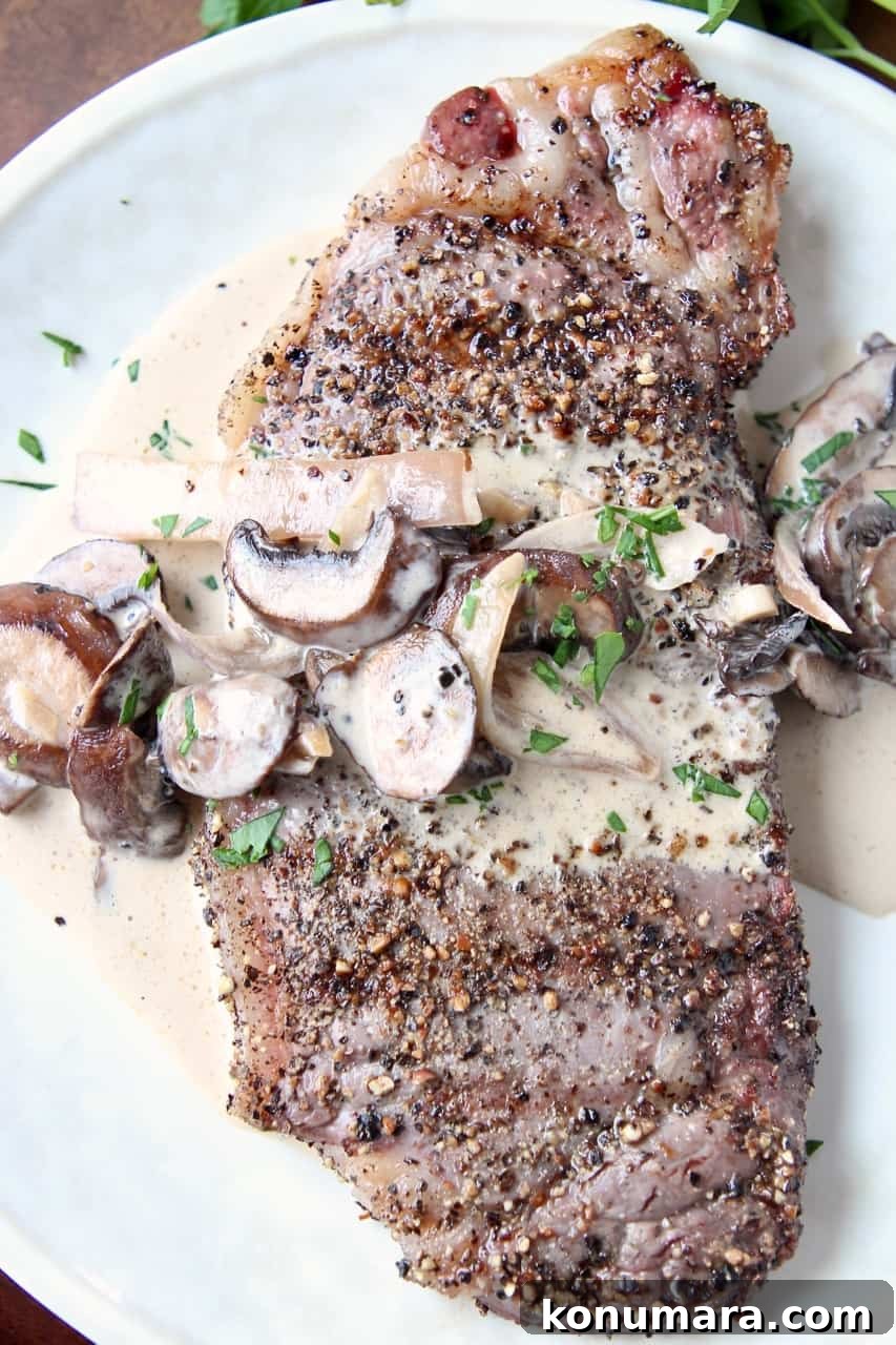 Grilled Peppercorn Crusted New York Strip with Mushroom Sauce 4 Overhead image of peppercorn steak on plate covered with mushroom sauce