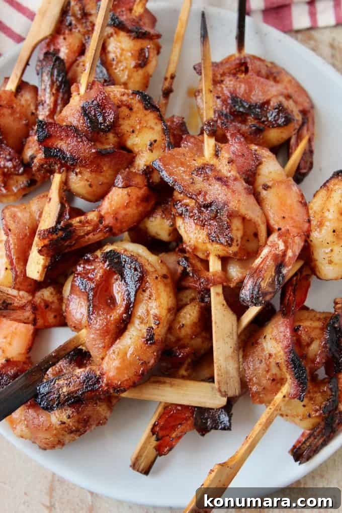 Grilled Bacon-Wrapped Shrimp Skewers 5 skewered bacon wrapped shrimp on plate
