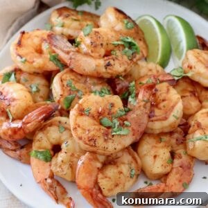 cooked shrimp piled up on plate with lime wedges