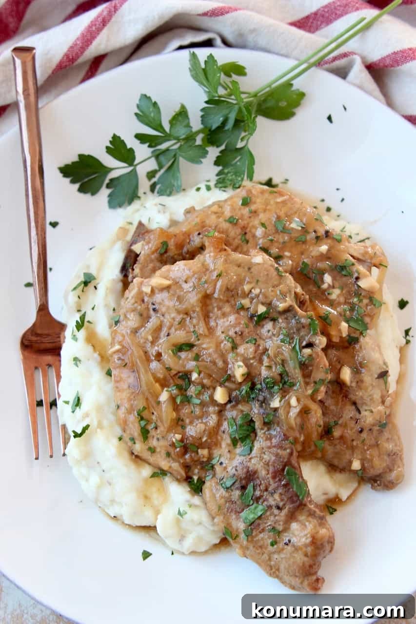 Slow Cooker Pork Chops with French Onion Gravy 6 Overhead image of two pork chops on plate with mashed potatoes and brown gravy