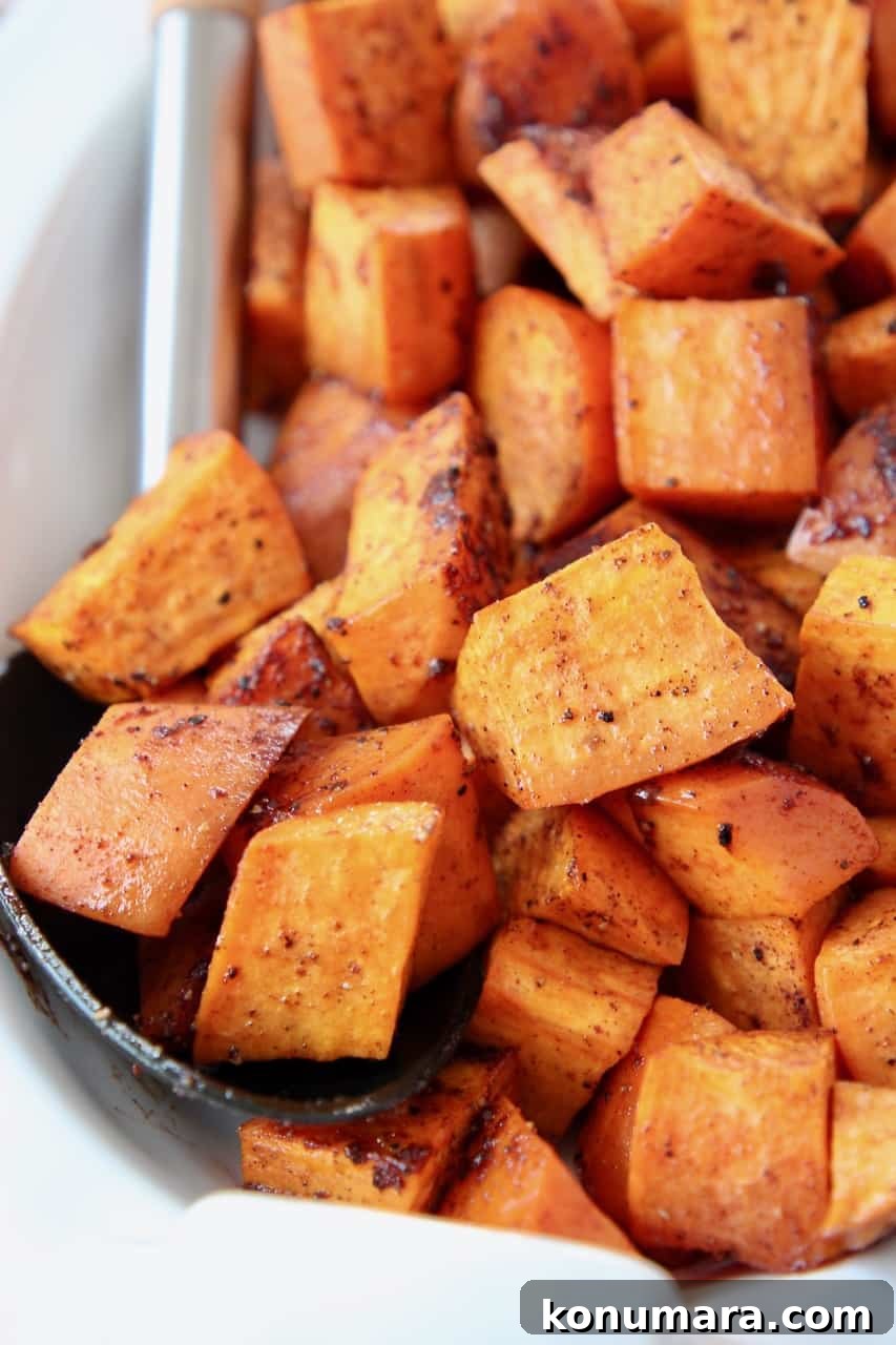 Roasted cubed sweet potatoes in bowl with serving spoon