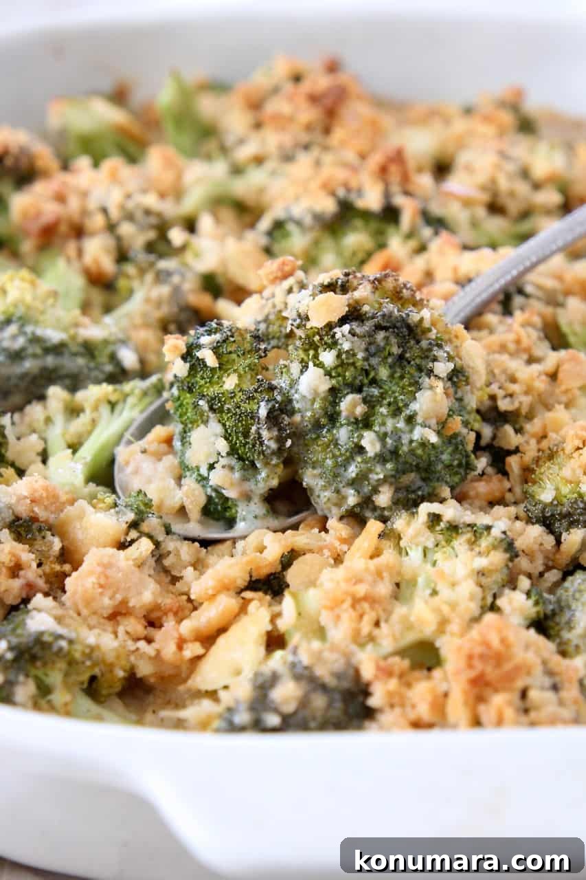 broccoli cheese casserole with serving spoon lifting broccoli out of the dish