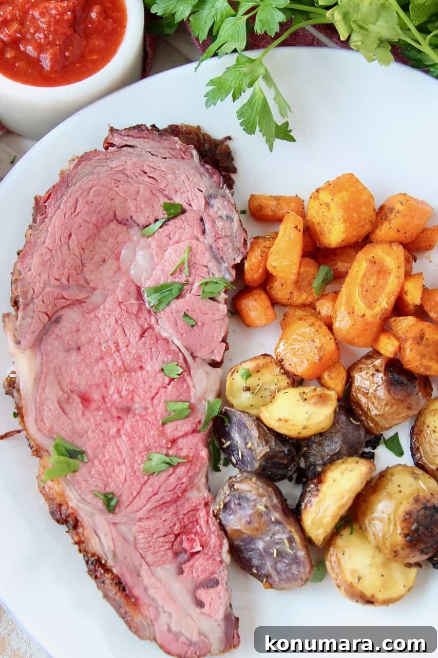 overhead image of sliced prime rib on plate with roasted vegetables