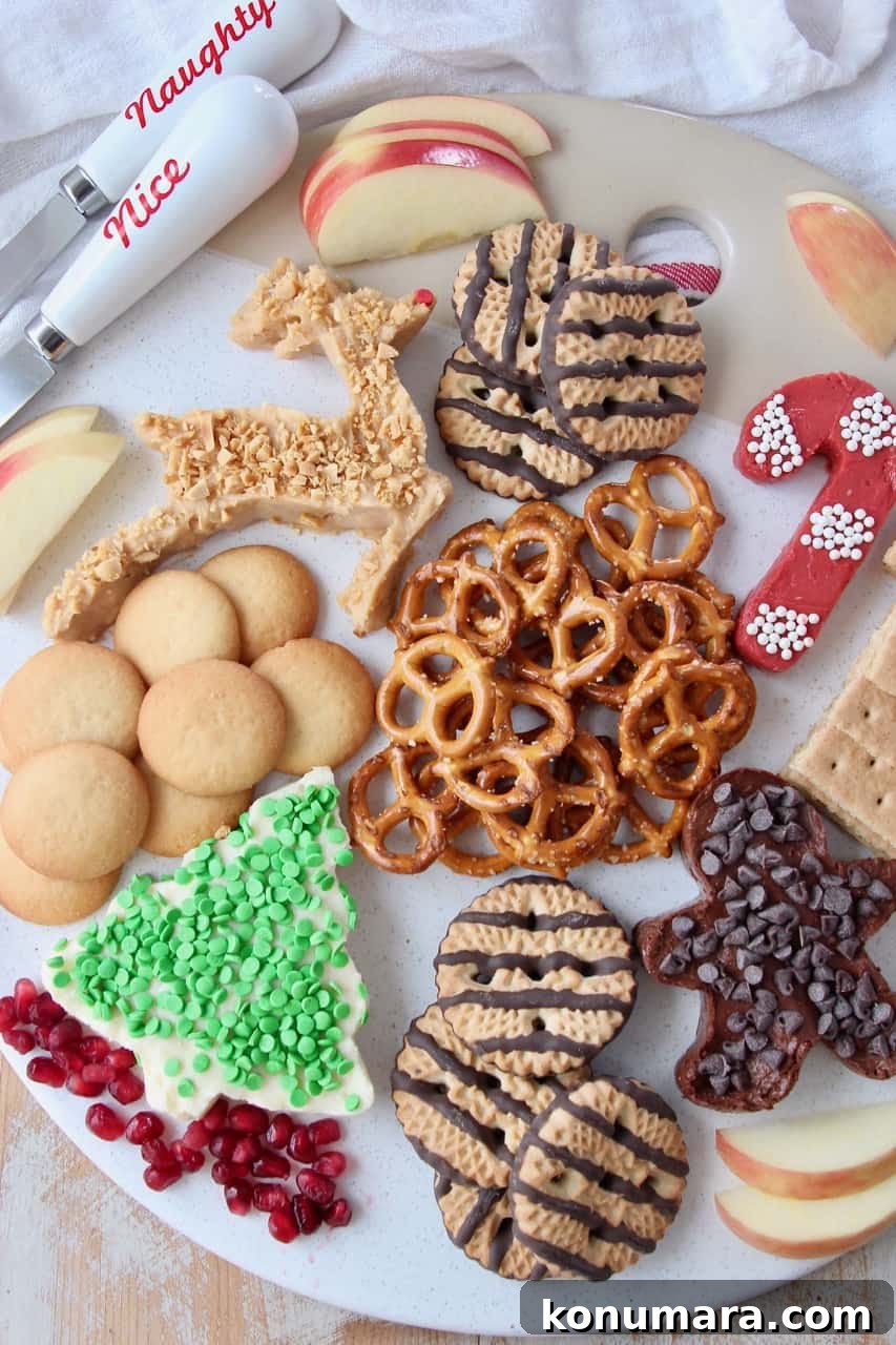 Overhead image of dessert board with pretzels, cookies and cream cheese dip in holiday shapes