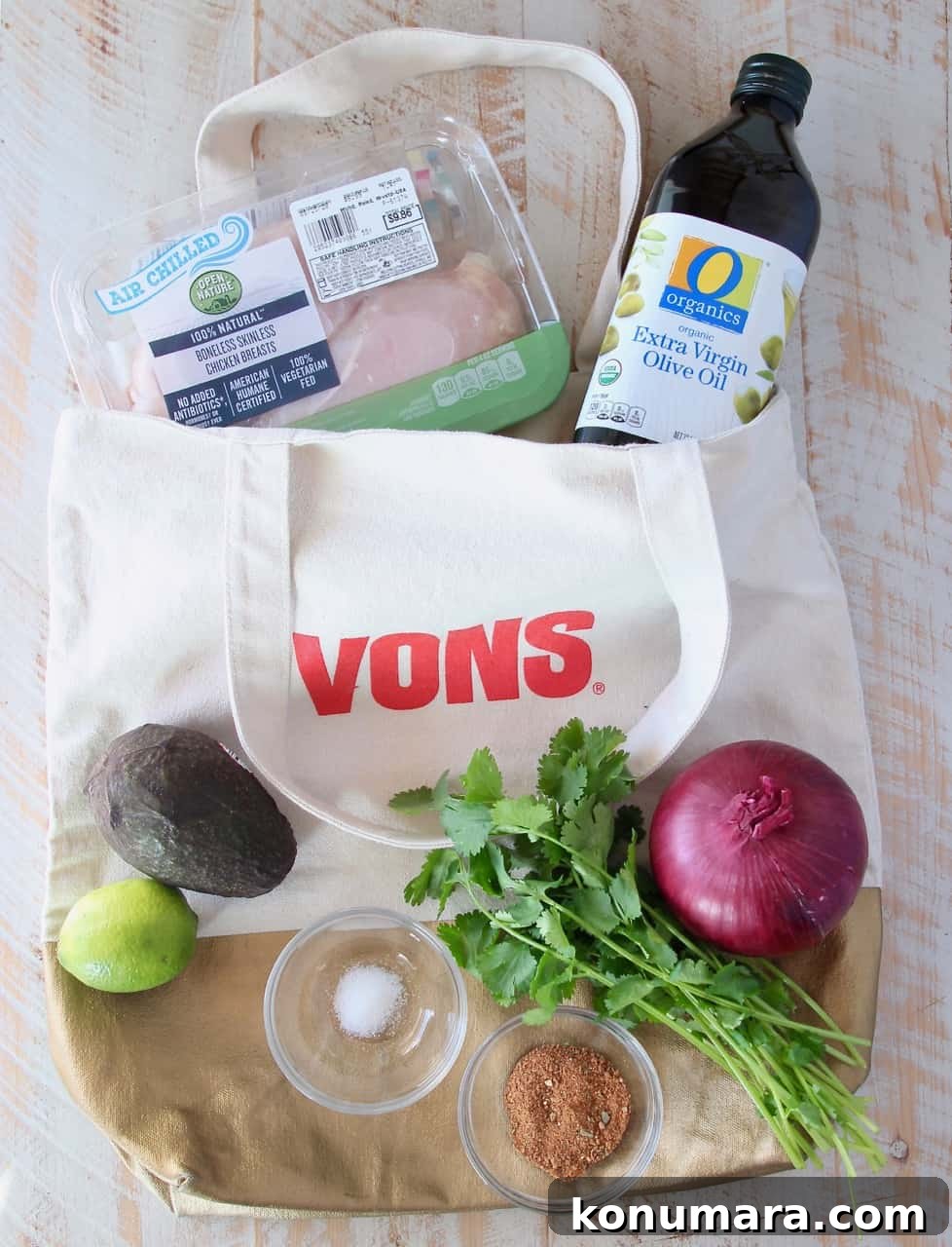 ingredients for guacamole stuffed chicken in a shopping bag on a white wood board