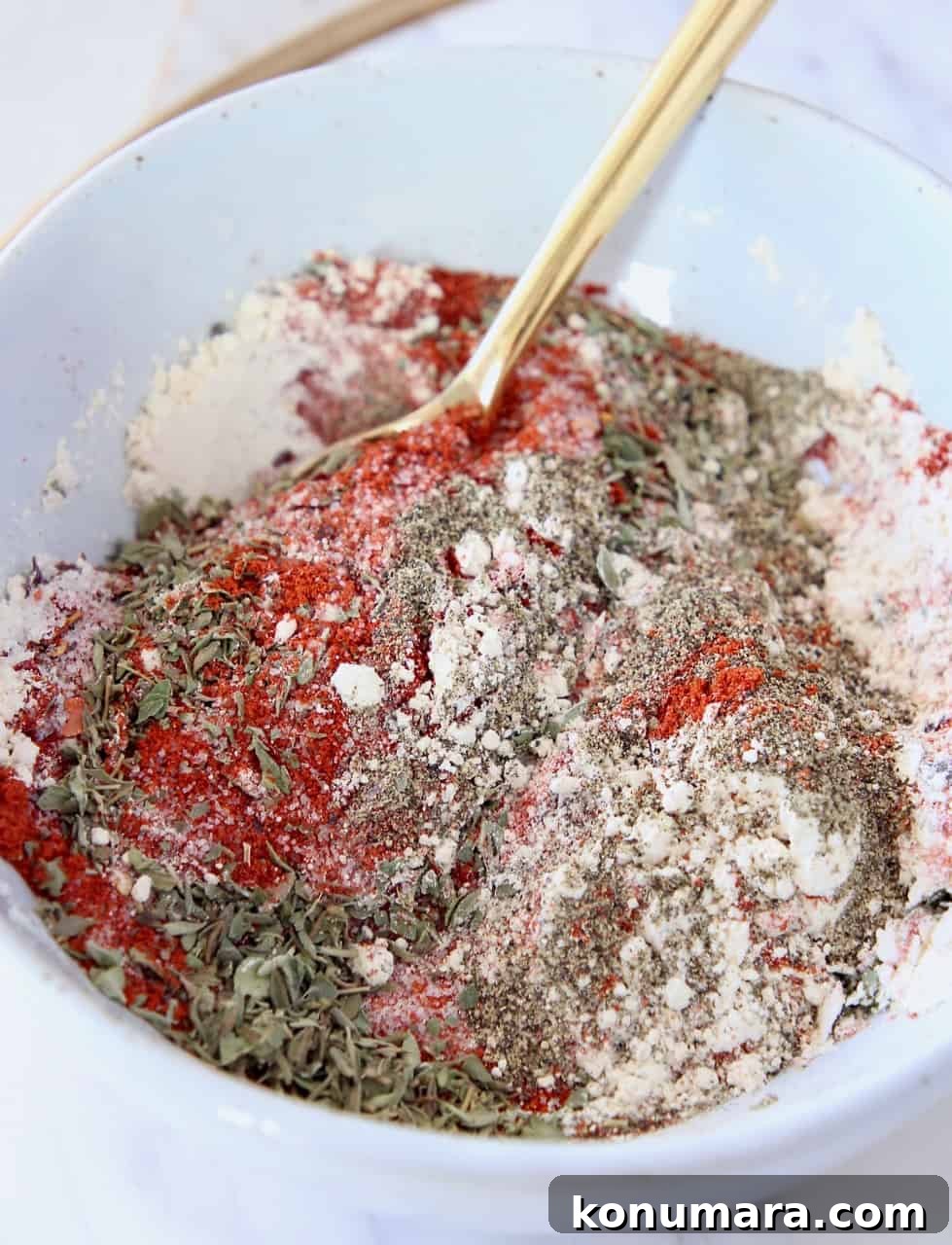 mixed spices and herbs in bowl with gold spoon