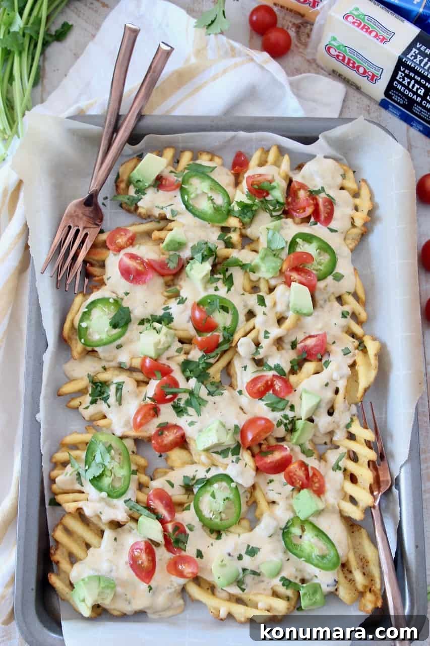overhead image of waffle fry nachos on sheet pan with forks
