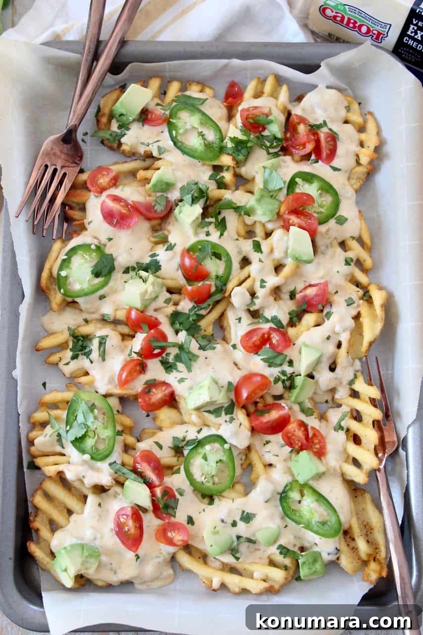 overhead image of waffle fry nachos on baking sheet with forks