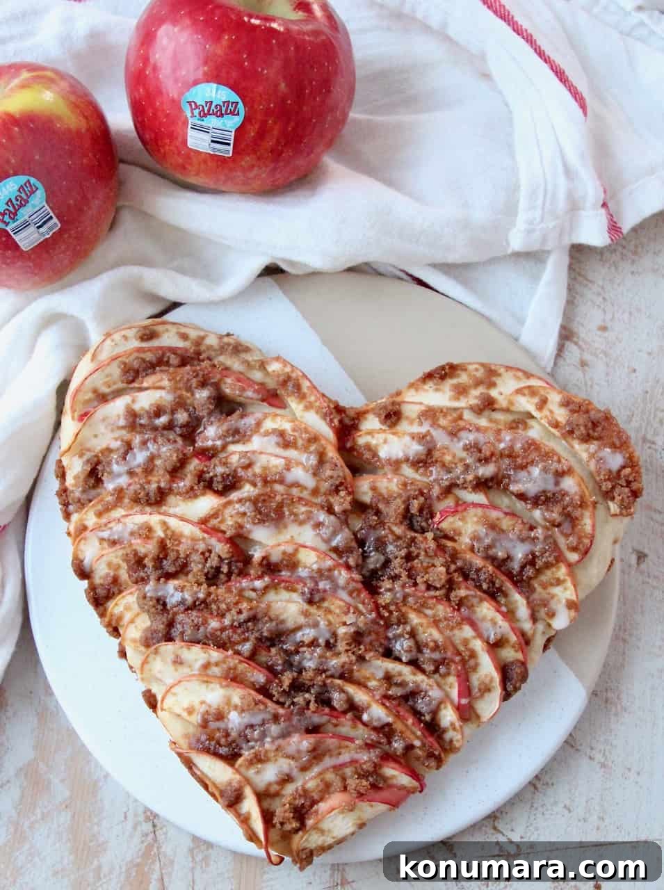 overhead image of heart shaped apple pizza on serving dish with fresh apples on the side