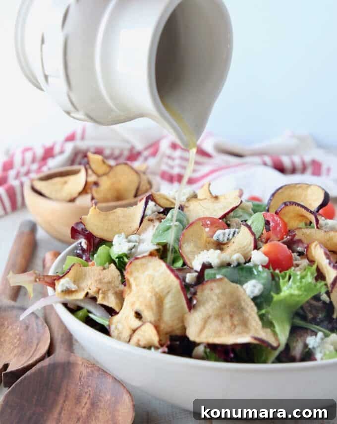 small pitcher pouring salad dressing onto salad in bowl