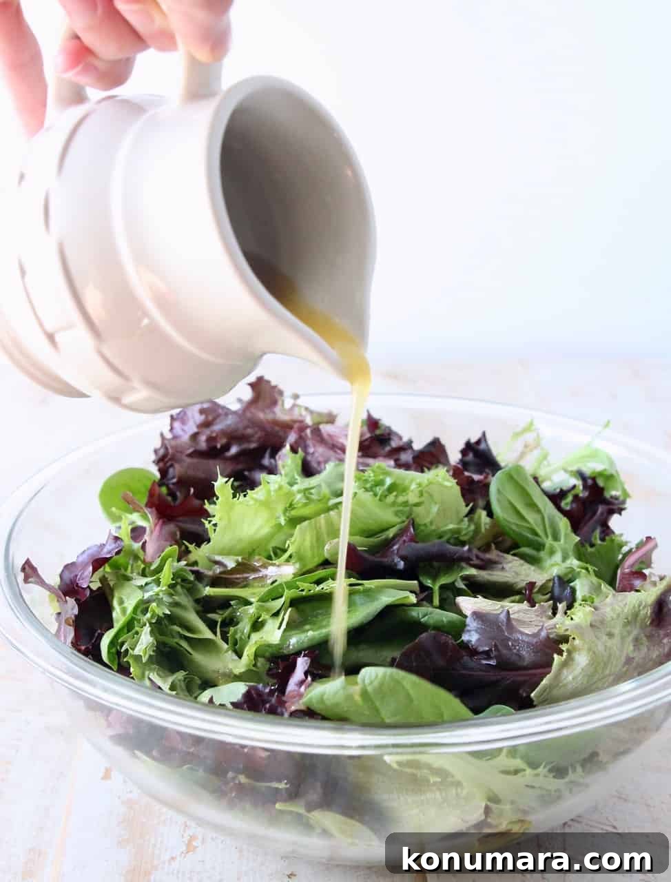 Panera-Style Fuji Apple Chicken Salad Recipe 3 small pitcher pouring vinaigrette dressing on salad in a glass bowl