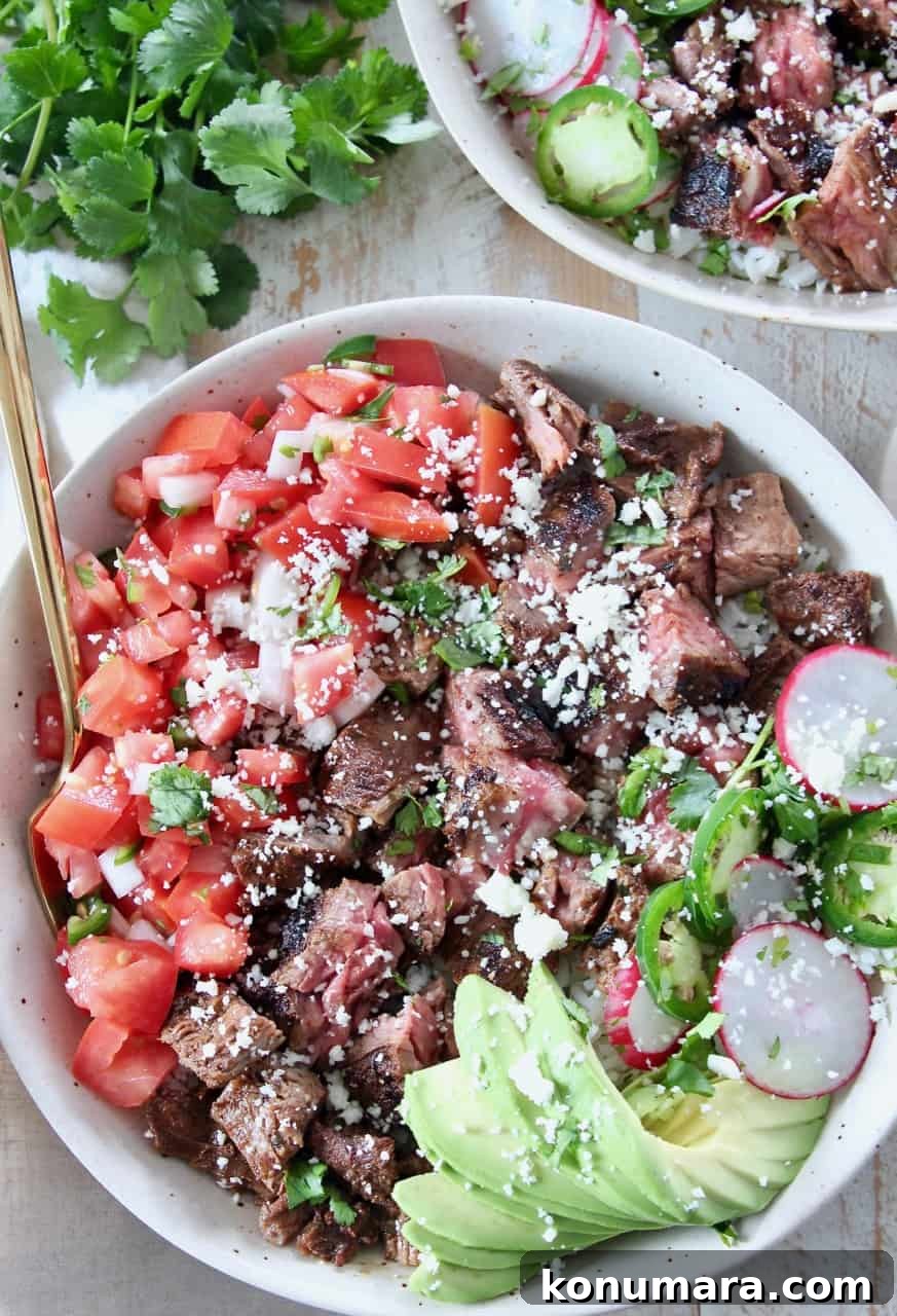 grilled steak in bowl with diced tomatoes and sliced avocado