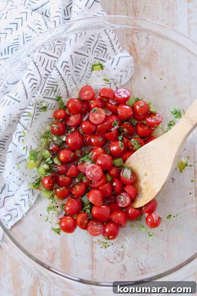 grape tomatoes with lemon herb dressing in glass bowl with wooden spoon