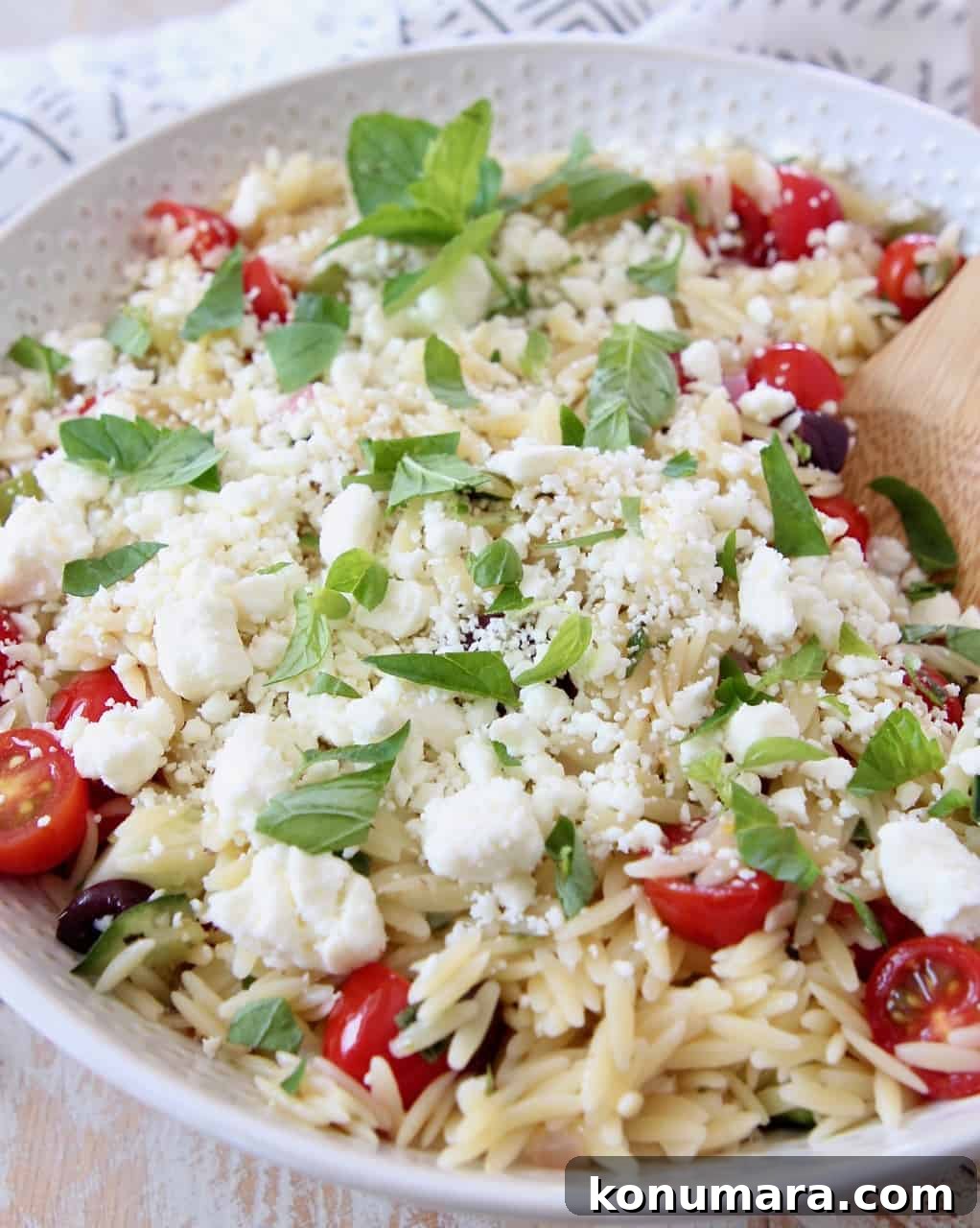 orzo pasta salad in bowl topped with fresh mint and feta cheese