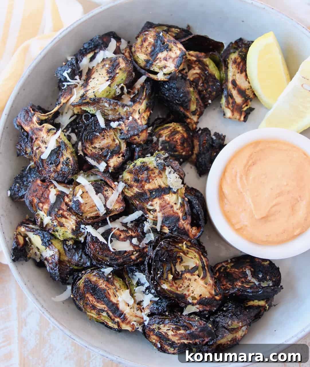 grilled brussels sprouts in bowl with harissa tahini dipping sauce on the side