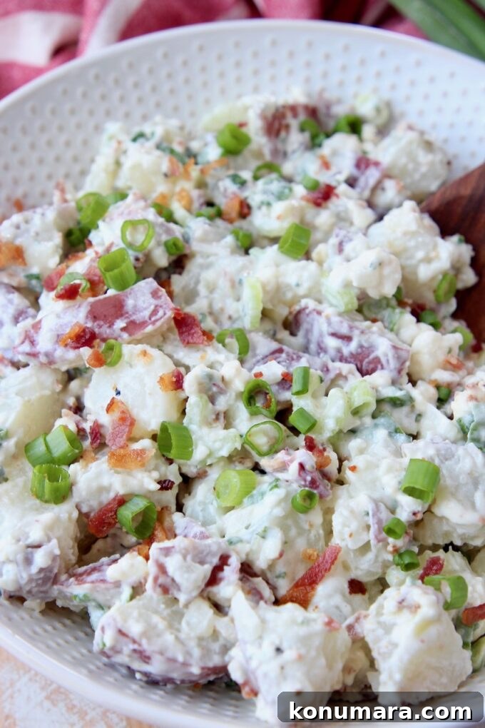 potato salad topped with crumbled bacon and diced green onions in bowl