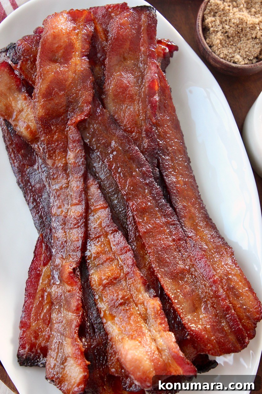 Sweet and Crispy Candied Bacon Recipe 2 slices of cooked bacon on top of each other on white plate