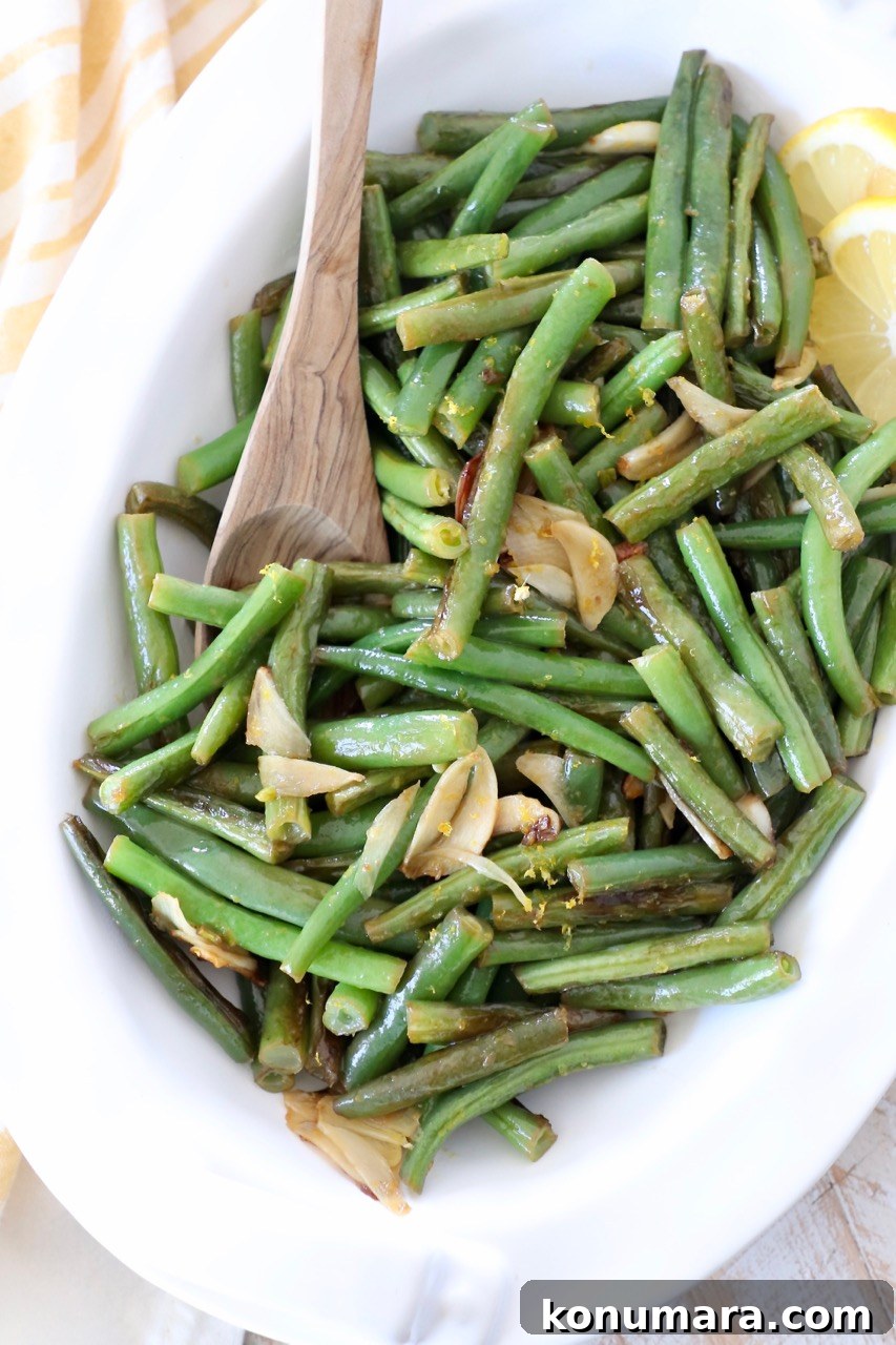 Sauteed Garlic Lemon Green Beans 6 garlic green beans in white serving dish with wooden serving spoon