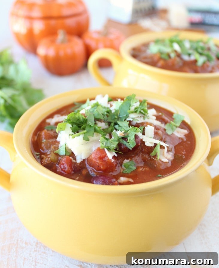 Pumpkin Chili Recipe with Black Beans 2 Yellow bowl filled with Pumpkin Chili garnished with melted cheese and cilantro.