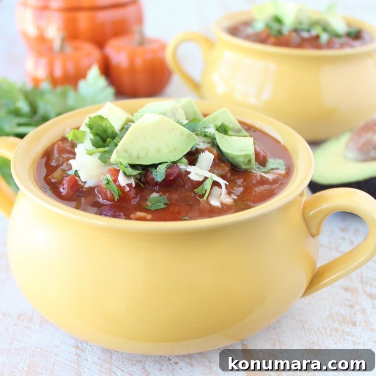 Pumpkin Chili Recipe with Black Beans 11 Yellow bowl filled with Pumpkin Chili garnished with melted cheese, avocado, and cilantro.