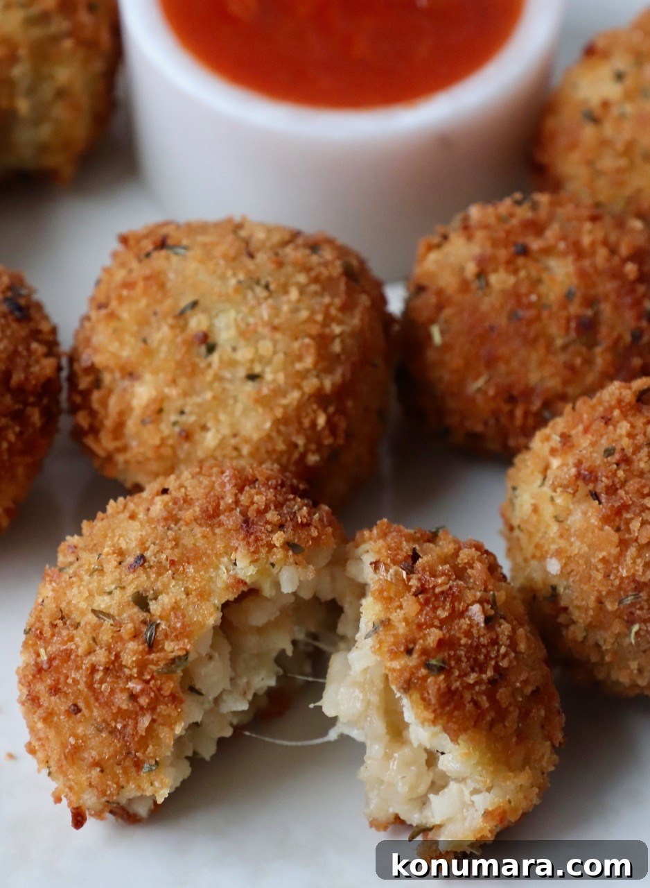 arancini on plate with bowl of marinara sauce