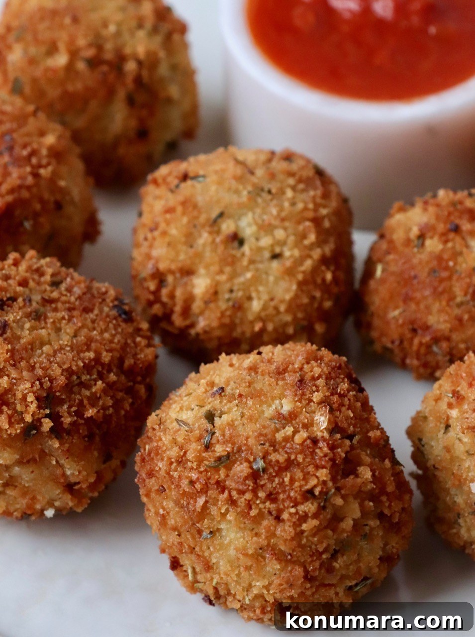arancini on plate with marinara sauce in bowl