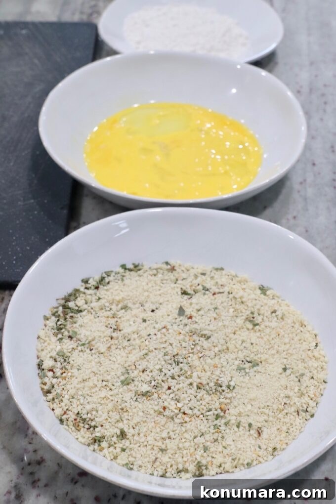 three bowls, filled with breadcrumbs, whisked eggs and flour