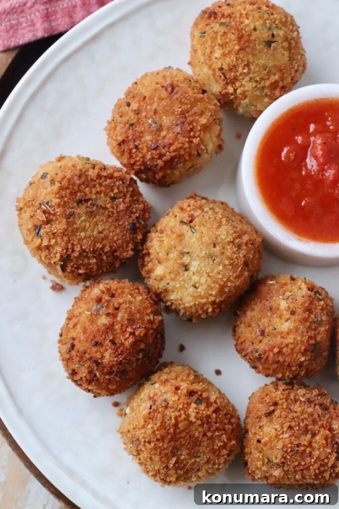 cooked arancini on plate with marinara sauce