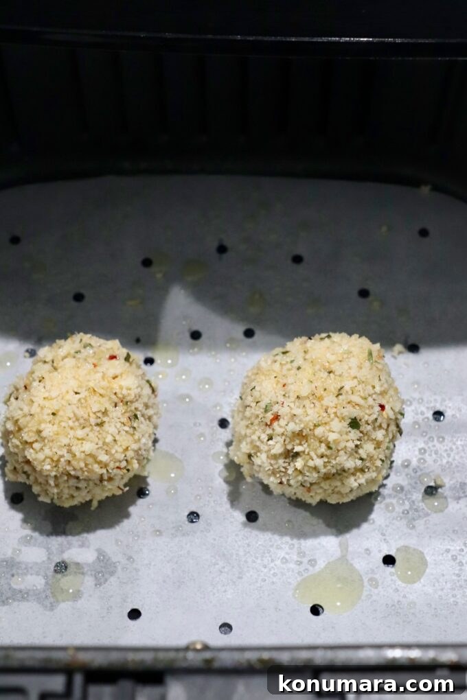 uncooked arancini in air fryer basket