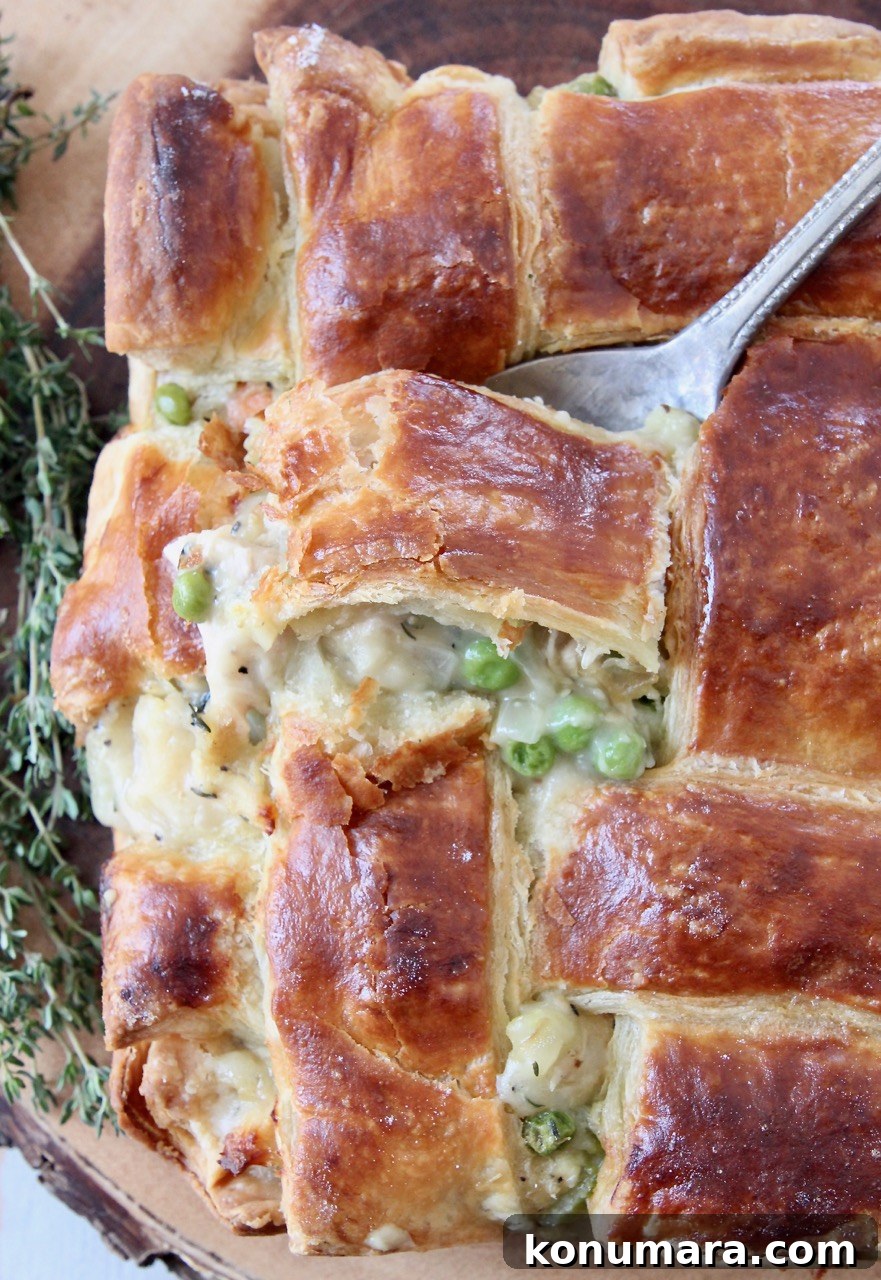 spoon dipping into baked chicken pot pie with puff pastry crust