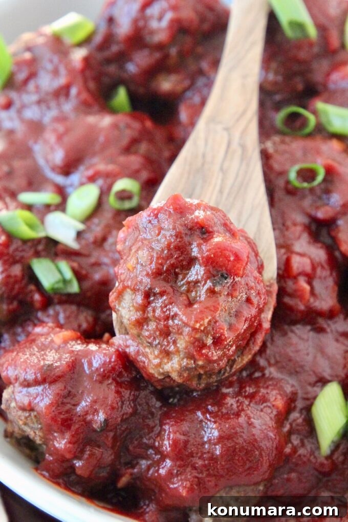 meatballs with bbq sauce in bowl and meatball on a spoon in the bowl