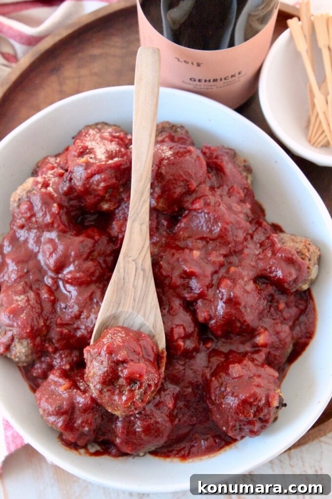 bbq sauce covered meatballs in bowl with wooden spoon
