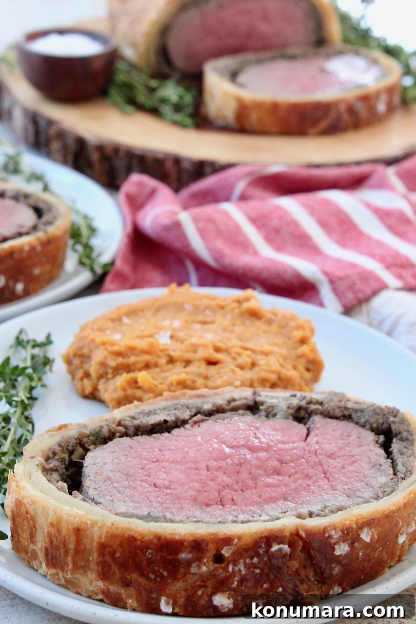 How to Make Classic Beef Wellington with Mushroom Duxelles 9 slice of cooked beef wellington on plate with mashed sweet potatoes