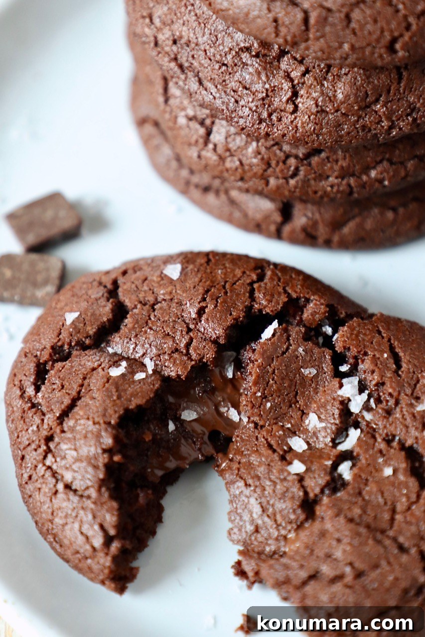 chocolate cookie pulled in half on plate next to stack of cookies