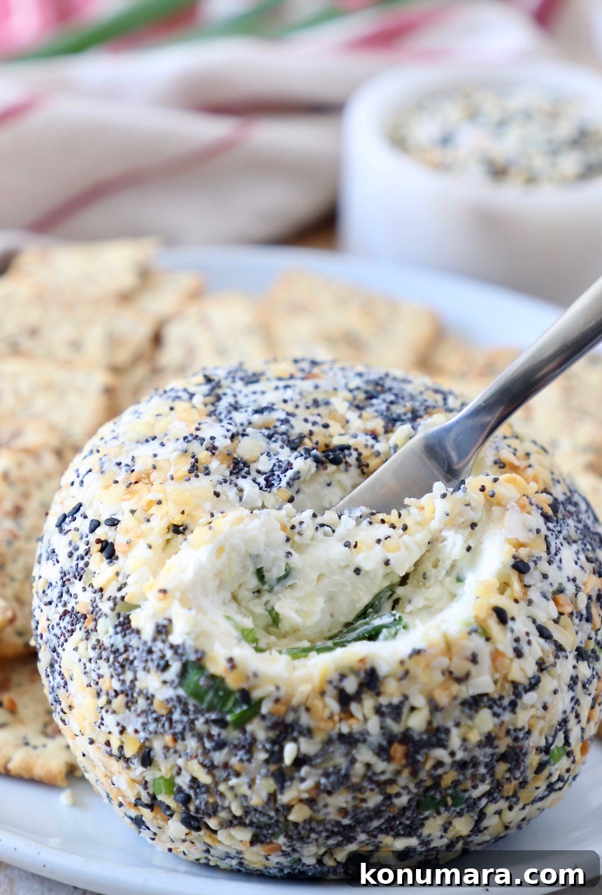 cheese ball with cheese spreader in the ball on plate with crackers