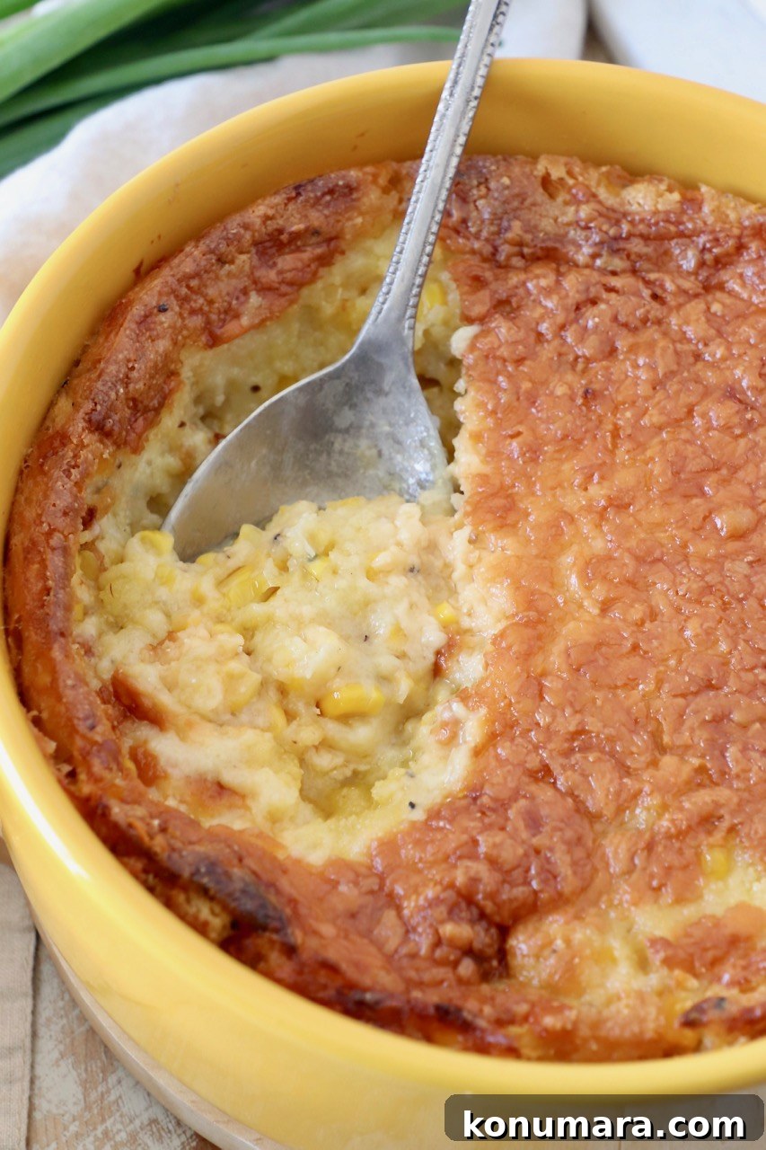 corn casserole in yellow round baking dish with serving spoon