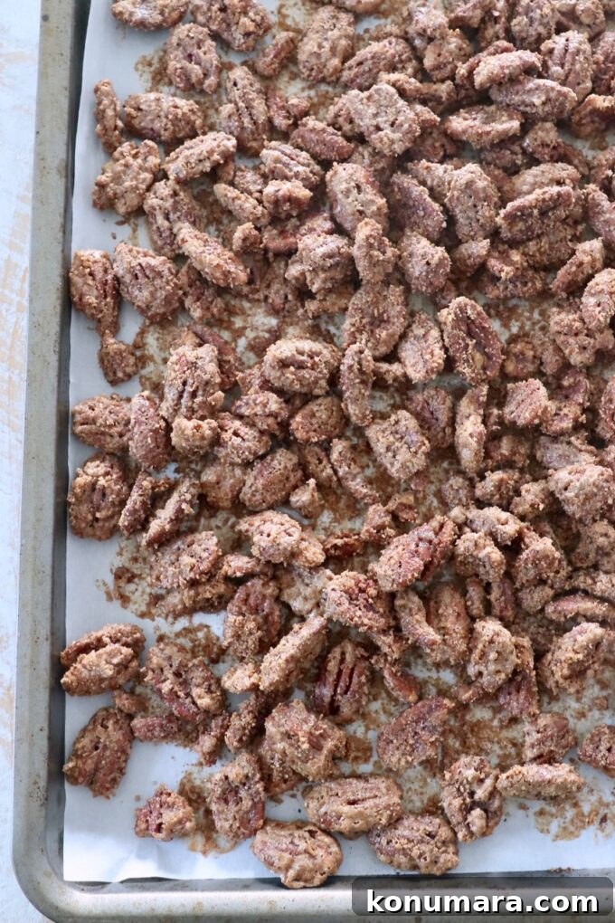 baked candied pecans spread out on baking sheet