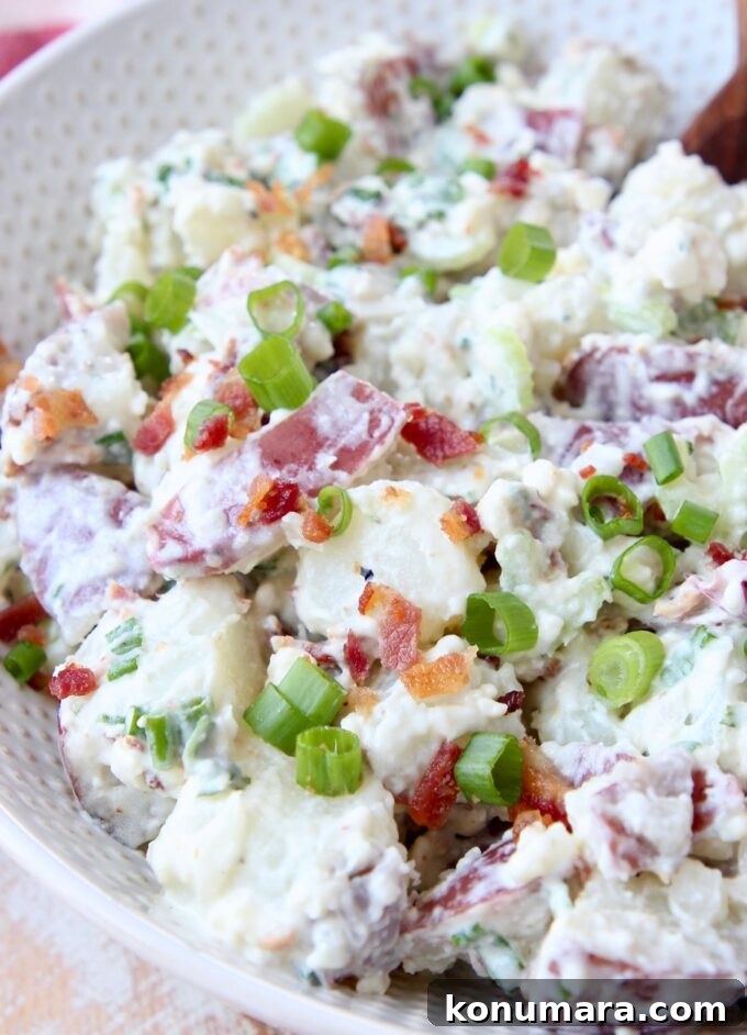 potato salad in white bowl topped with diced green onions